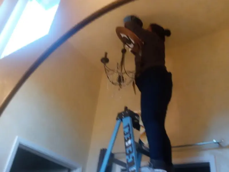 Electrician installing a chandelier in a Royse City residence